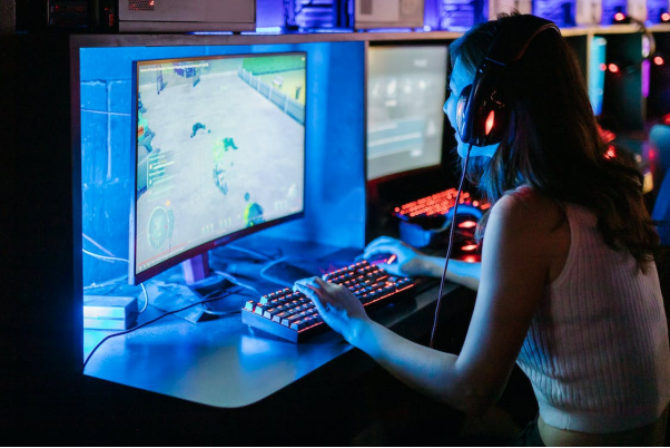 A gamer girl is smiling while she plays a game on her PC
